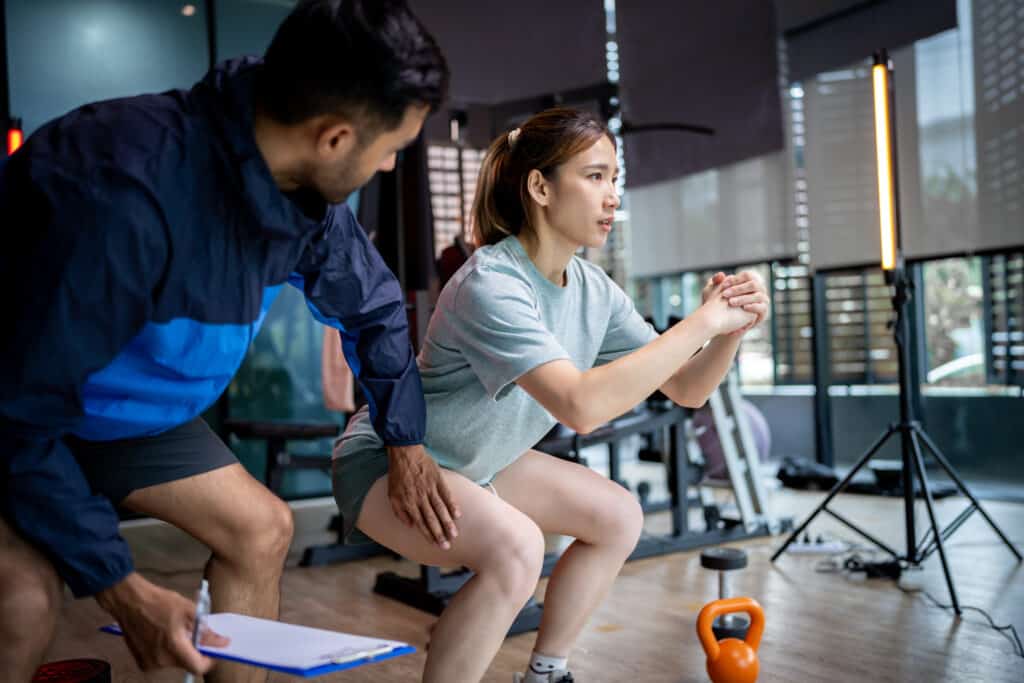 Male personal trainer and female client working out in a gym setting.