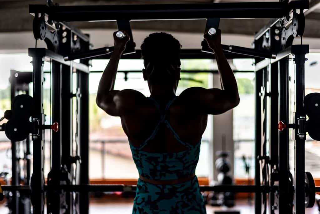 A black female athlete performing an upper body strengthening exercise by completing a pull-up
