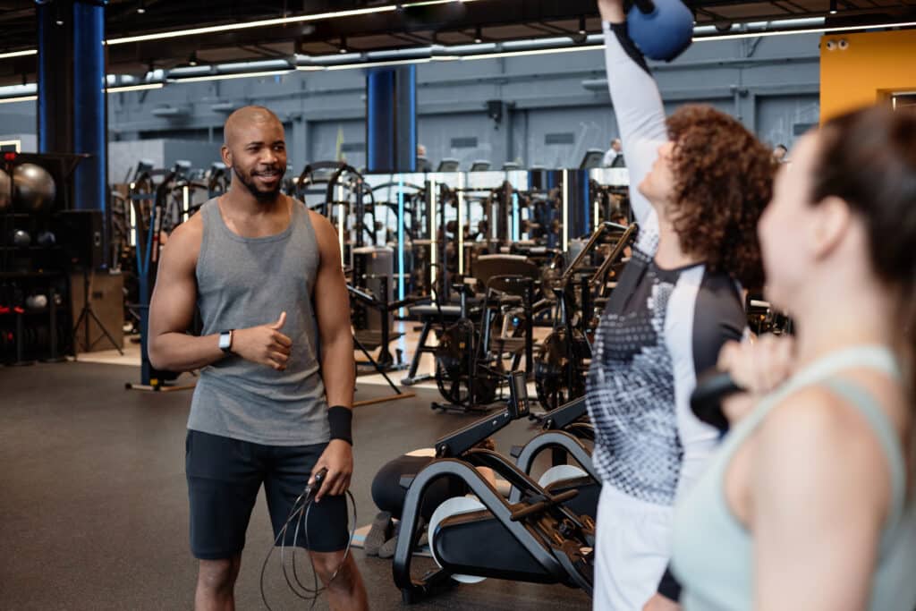 Ftness coach watching client in gym giving instructions for weight lifting training