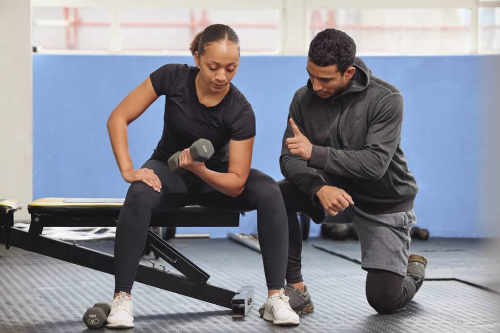 Shot of a young woman exercising with a personal trainer at the gym.