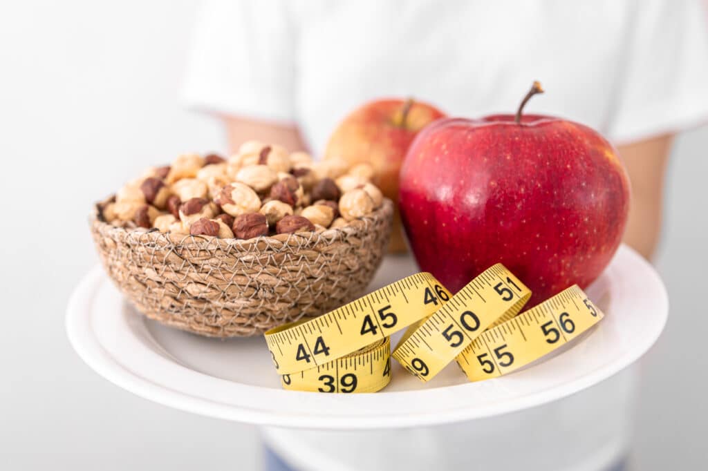 Close up of a plate of apples and hazelnuts on a blurred background, the concept of losing weight, healthy eating.