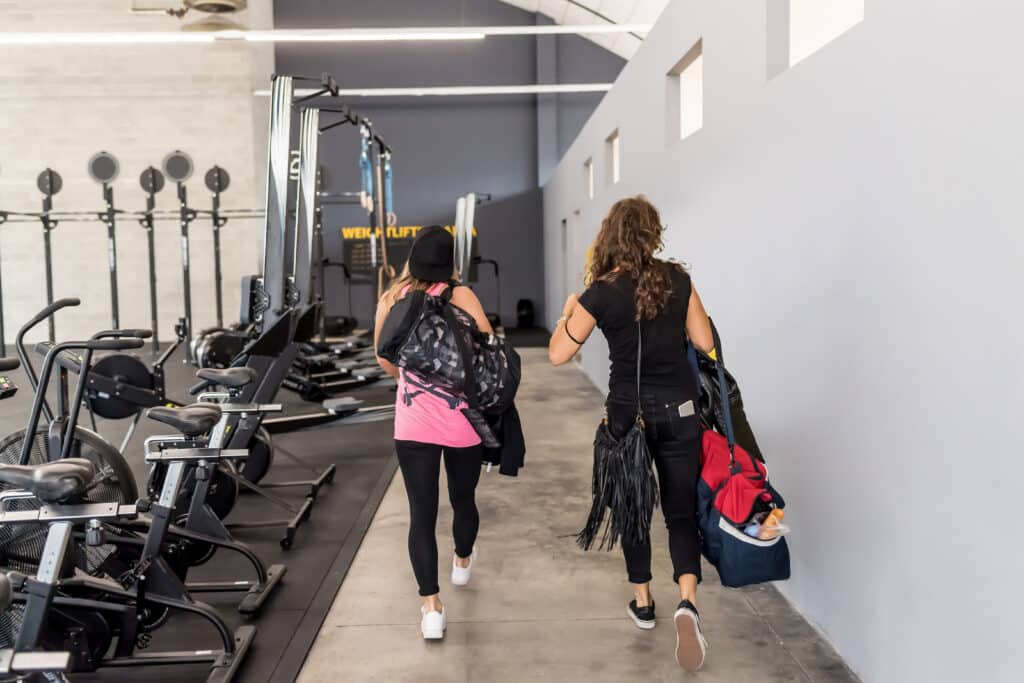 Two women holding gym bag walking indoors
